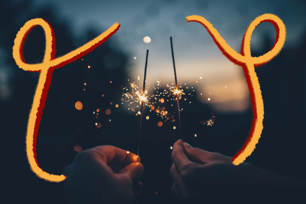 Which zodiac sign should you be kissing this New Year and what you should focus on in your love life this upcoming year - two hands holding sparklers with yellow and red swirls on picture