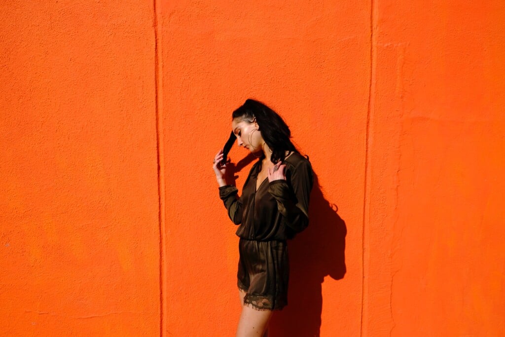 Tips and tricks to perfect your personal style - fashionable woman standing in front of orange wall