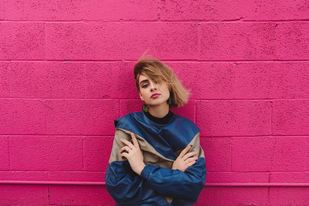 Top fashion trends for 2023 - woman in fashionable blue jacket in front of magenta brick wall