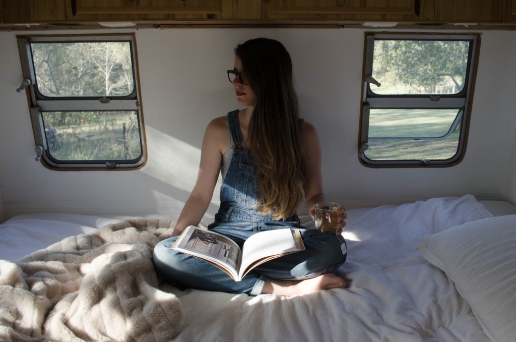 Aquarius- graphic novels and manga - model sitting on bed in small camper van land with a book in lap