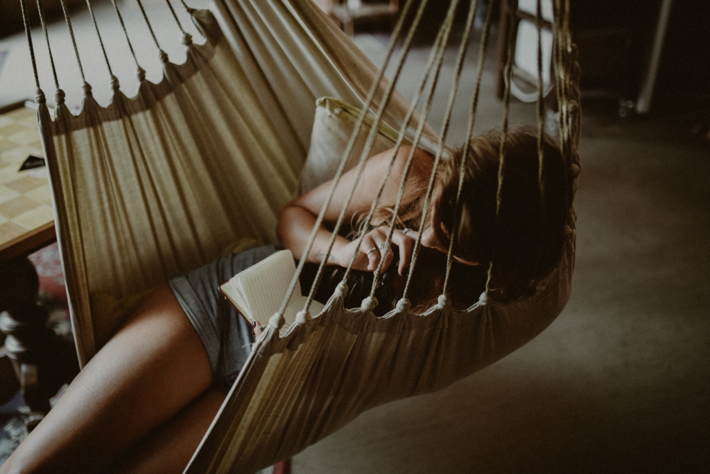Cancer - Romance - woman sitting in indoor hammock seat reading a book