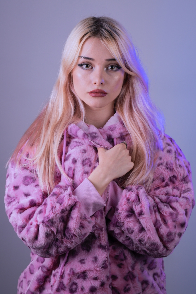 Woman covering body with oversize fuzzy purple jacket