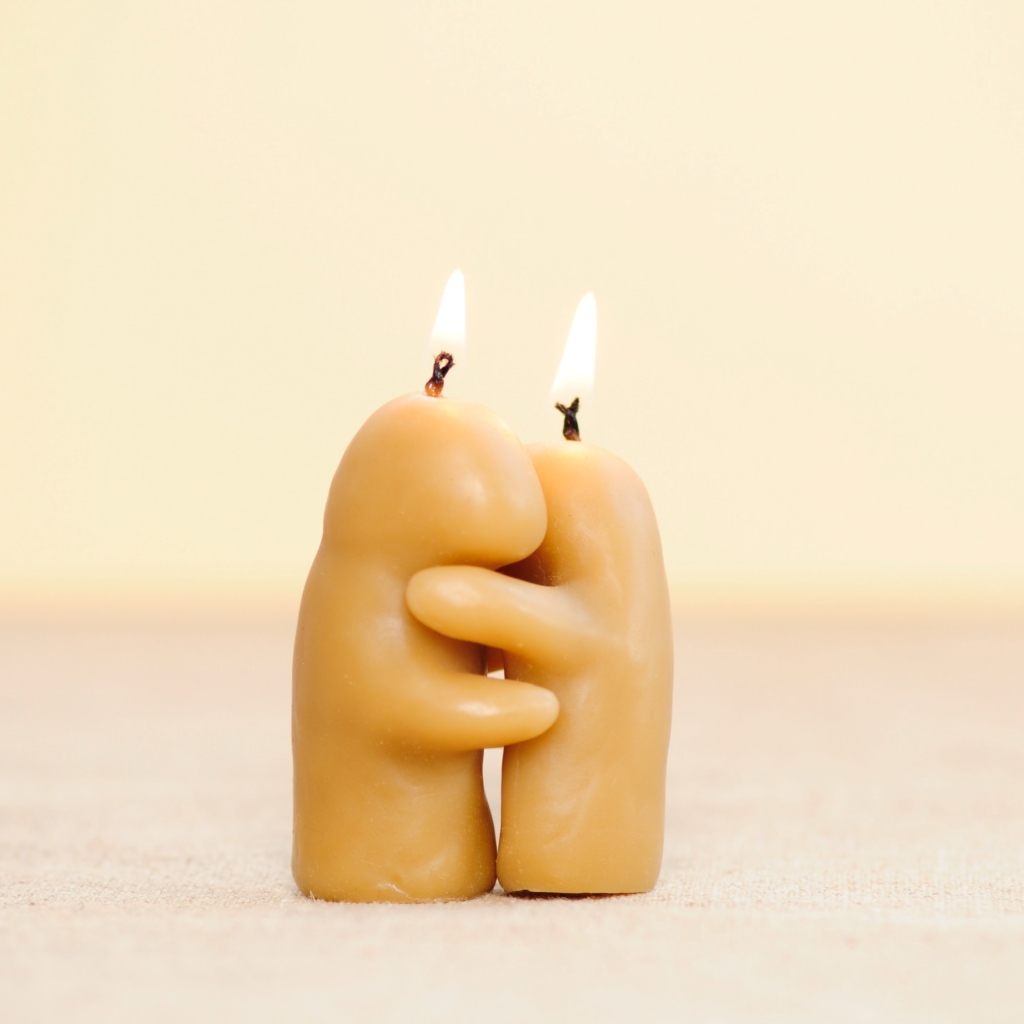 Make your own candles - two lit candles shaped as human-like blobs hugging each other