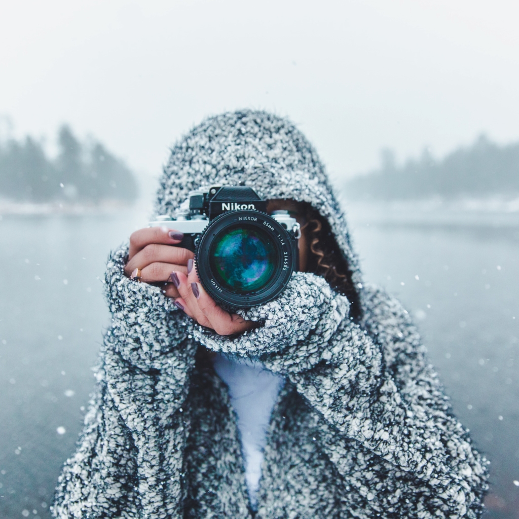 Pick up nature photography - woman holding camera in snowy winter landscape