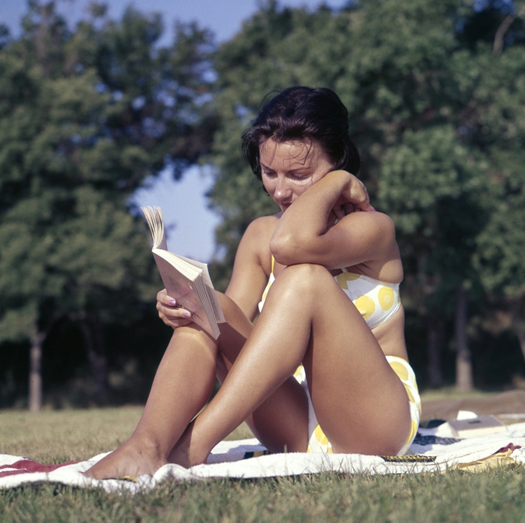 Libra - folklore and fables - model in bikini sitting on towel outside reading a book