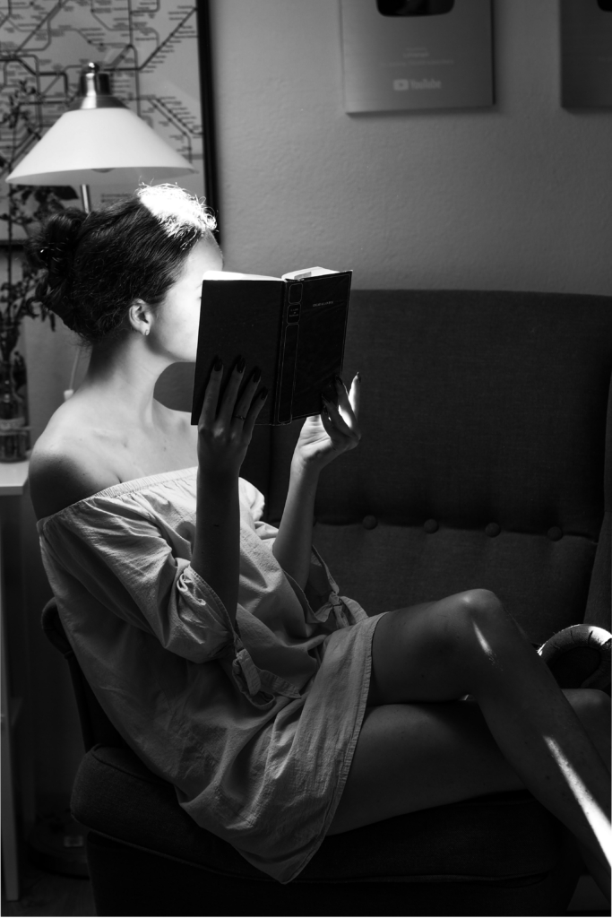 Scorpio - mystery - black and white of woman sitting on couch reading a book with her face partially hidden from view