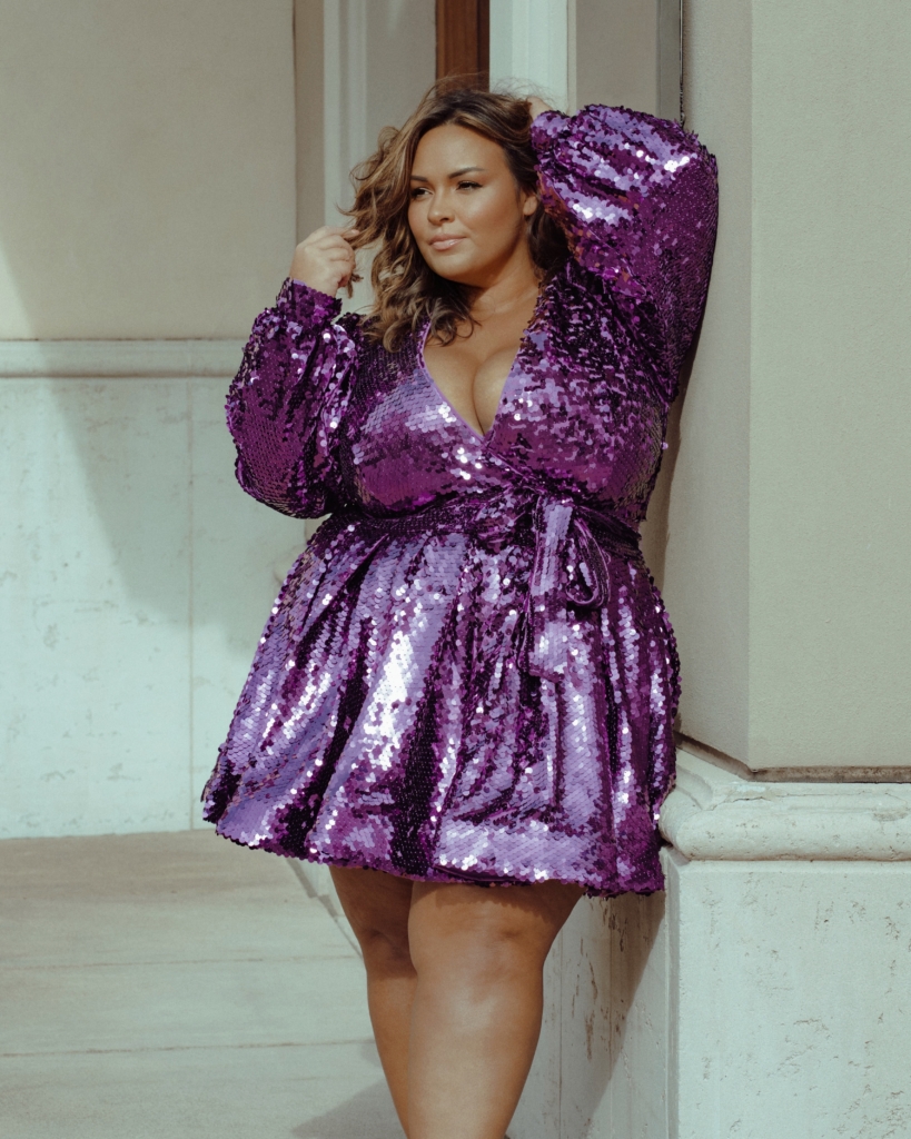 Plus size woman wearing purple sparkly glittery dress with bow tie around waist