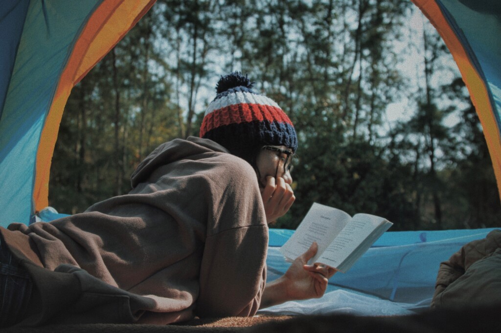 Sagittarius- philosophy- woman in tent in forest area lying down and reading a book